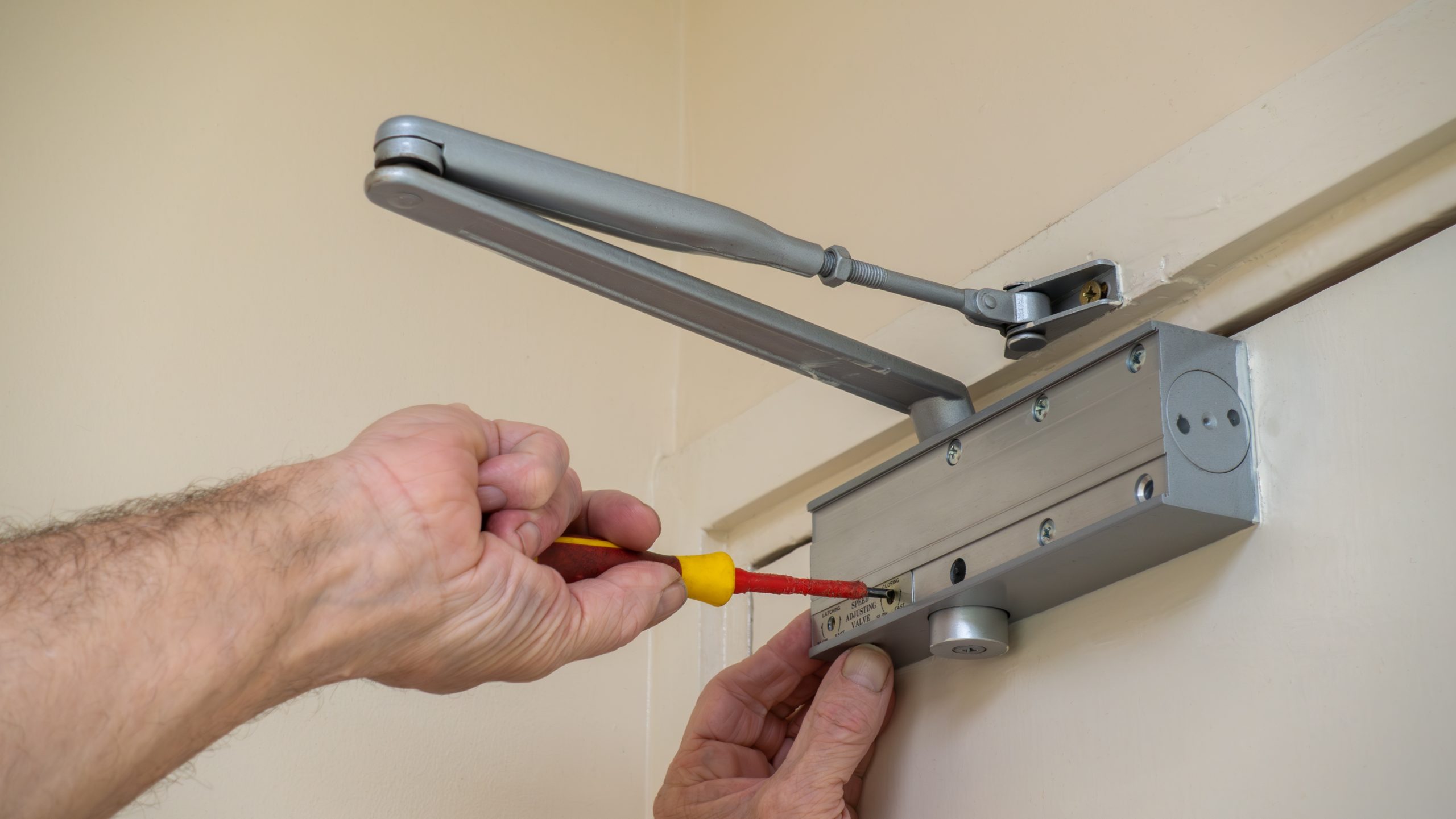 Technician uses screwdriver to maintain door closing mechanism